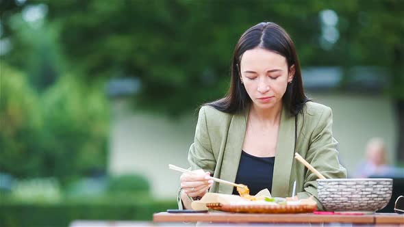 Young Woman Eating Take Away Noodles on the Street