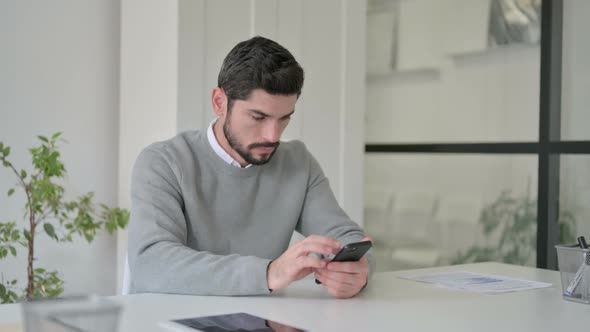 Young Man Using Smartphone in Office