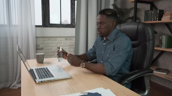 African American Man Applying Sanitizer Spray Rubbing Hands Before Distance Computer Work From Home