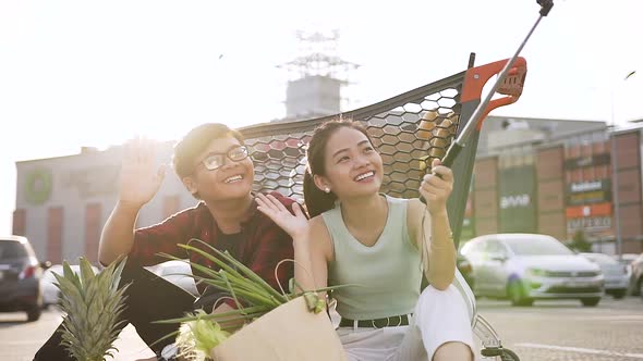 Asian Man and Woman Waving Hands and Saying Hallo While Making Selfie