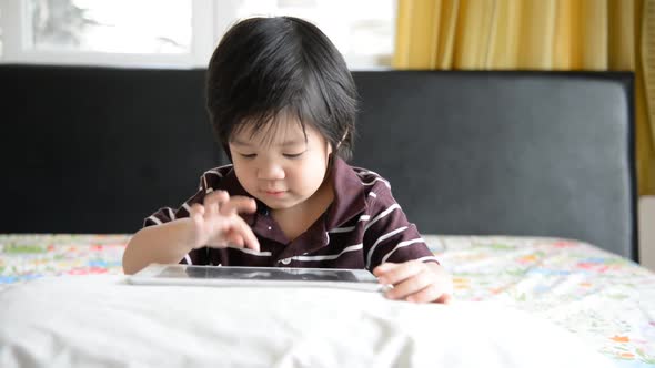 Asian Baby Using Tablet On Bed