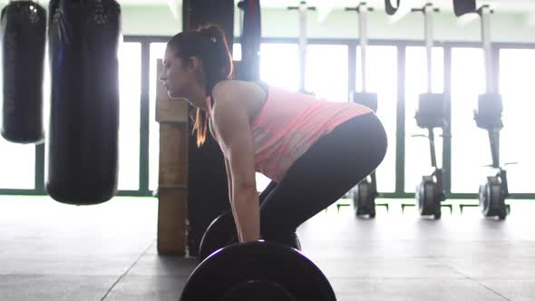 Footage of a pregnant female model doing squats in a gym trying to keep fit in her fourth trimester