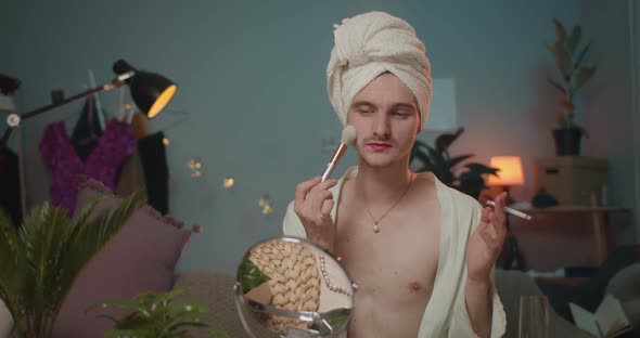 Man Transgender Using Brush and Applying Face Powder Hile Smoking Cigarette. Young Man Transvestite