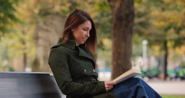 Woman Reading Book Sitting on the Bench in a Park