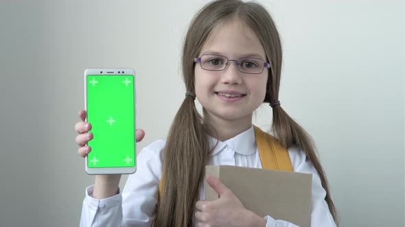 Schoolgirl with School Bag in White School Blouse and Glasses Holding Books and Shows Phone with