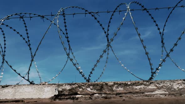 The Fence with Barbed Wire on the Background of a Gloomy Cloudy Dark Blue Sky