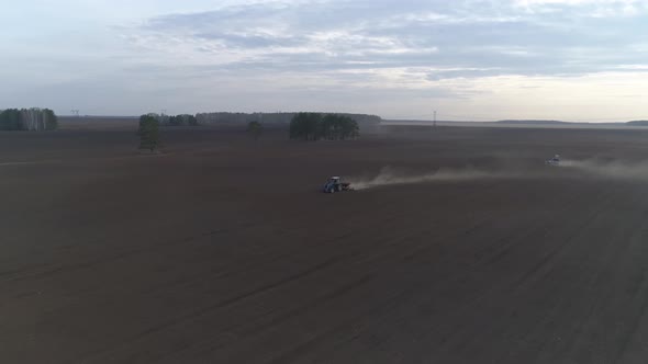 Two tractors plow in a huge field, Spring, evening 01