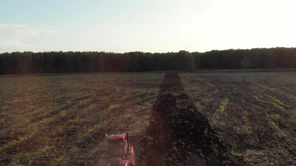 Red Tractor With Plow Working In Field