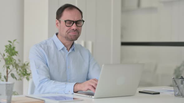 Middle Aged Man with Laptop Shaking Head As No Sign