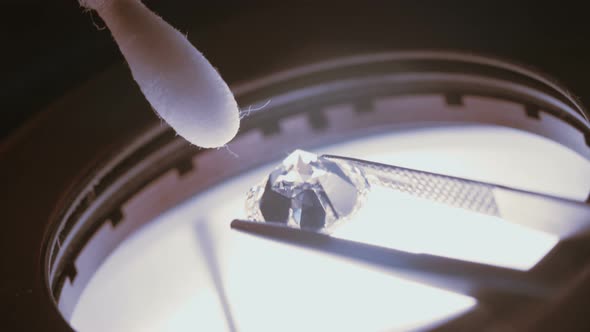 A gemologist inspecting a large clear diamond under a microscope