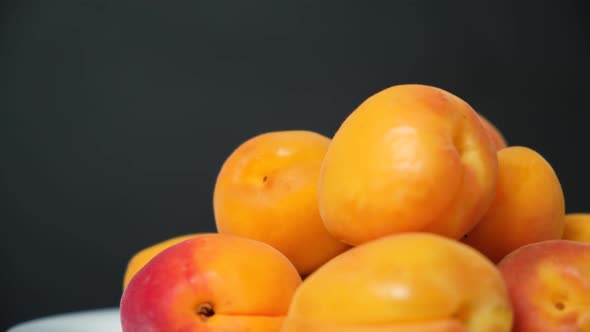 Ripe Apricots on a Plate Spin in a Circle on a Black Background
