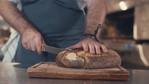 Young chef cutting bread