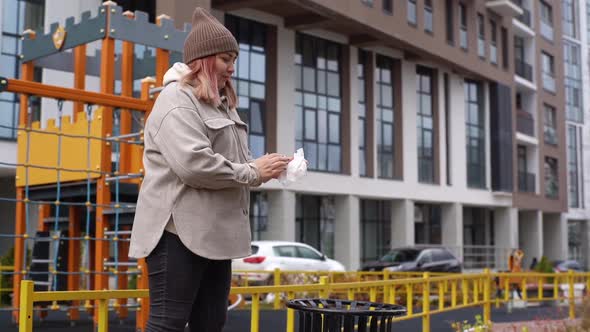 Side View of Woman in Warm Hat and Outerwear Using Antibacterial Wet Wipes to Clean Disinfect Hands