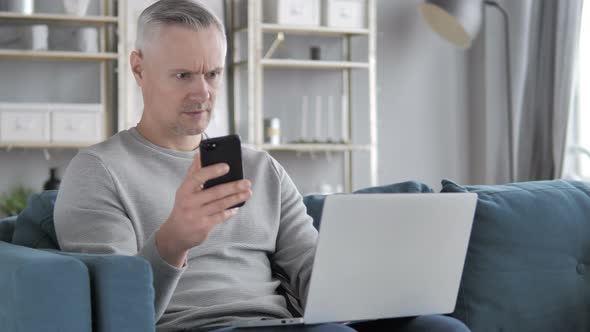 Gray Hair Man Using Smartphone and Laptop for Work