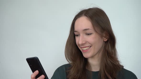 A Young Woman Emotionally Reading Messages on Her Smartphone