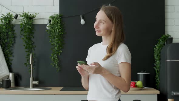 Smiling Woman Using Smart Phone in Kitchen