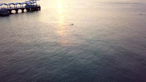 A dynamic aerial footage of a swimming man coming from a nearby jetty across the sea while under the