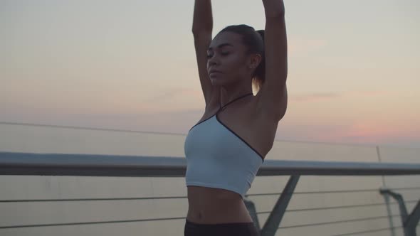 Black Fit Female Runner Stretching Arms at Sunrise