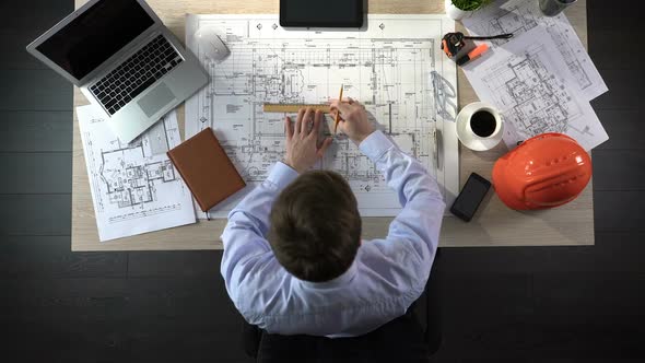 Architect Checking Drawing of Building, Making Notes to Discuss With Colleagues