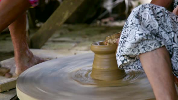 Assistant Rotates Wheel By Bare Foot Potter Models Vase