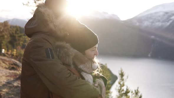 Happy Young Couple in Winter Coats Embracing People Hugging Looking at Stunning View on Lake and