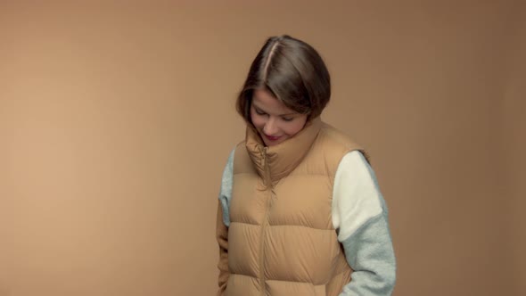 Caucasian Brunette Model in Studio on Beige Background Wear a Sleeveless Jacket