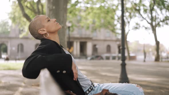 Relaxed bald woman sitting on the bench