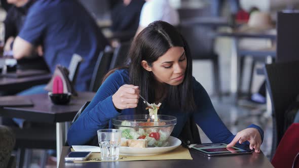 pretty young asian woman drinking and using tablet in a restaurant