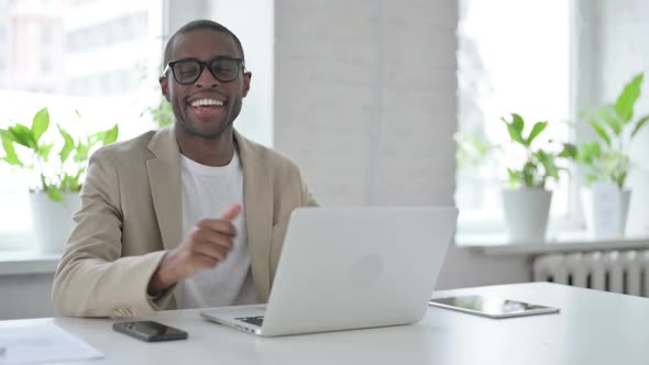 African Man Showing Thumbs Up Sign While Using Laptop in Office