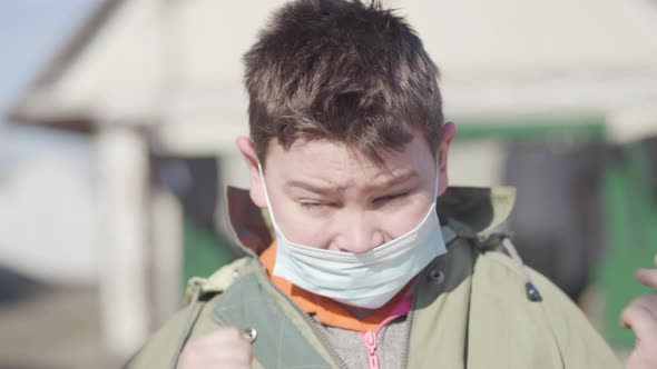 Portrait of Ill Caucasian Little Boy in Face Mask Rubbing Eyes and Sneezing. Close-up of Sick Child