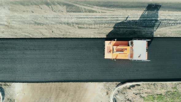 Road Construction Site. Top View of a Paving Machine Riding Along the Hot Asphalt