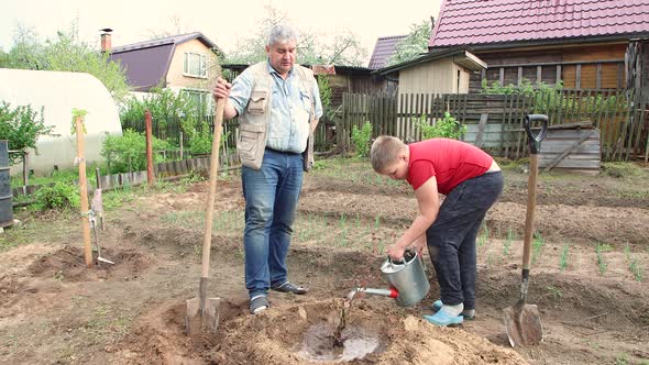 Father and Son Planted a Tree the Boy Poured Water From a Watering Can