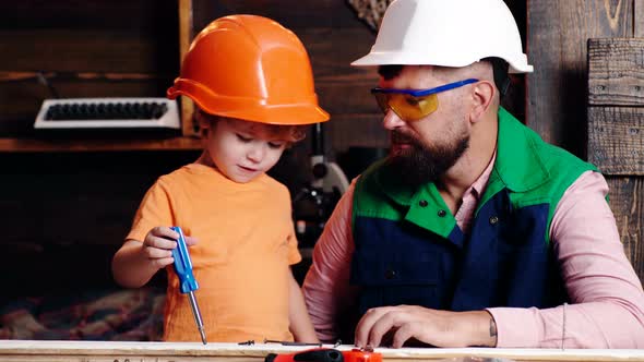 Father and Son Working Together. Child Learning Use Tools with Dad. Parent in Protective Helmet