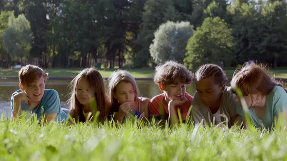 Joyful Multiracial Preteen Friends Lying on Park Grass Together