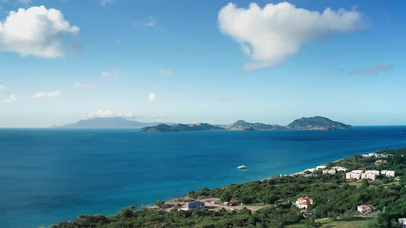 Drone camera captures a white yacht in front of a city in rainforest in Saint Kitts and Nevis