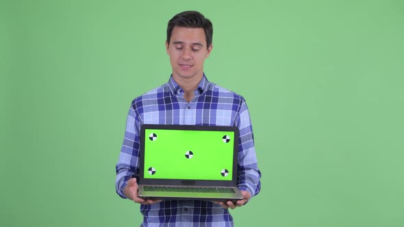 Happy Young Handsome Hipster Man Talking While Showing Laptop