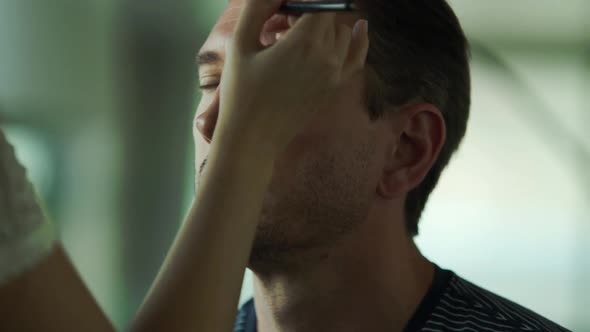 Man getting make-up done by makeup artist