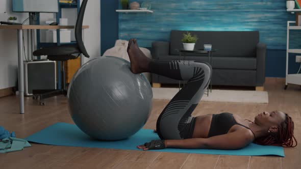 Slim Woman with Black Skin Doing Abs Exercise Using Fitball Flexing Abdominal Muscles