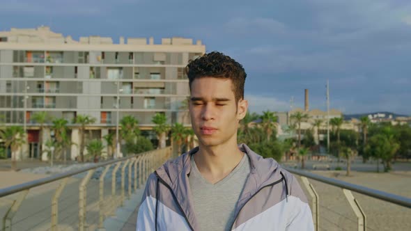 Young attractive athlete walking towards the camera on Bridge in the morning.