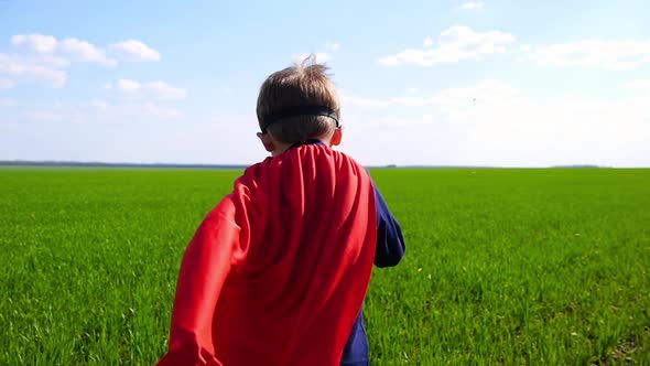 A Child in a Red Raincoat Runs Through a Green Field on a Sunny Day