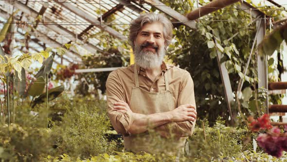 Cheerful Senior Farmer Smiling and Posing for Camera in Greenhouse