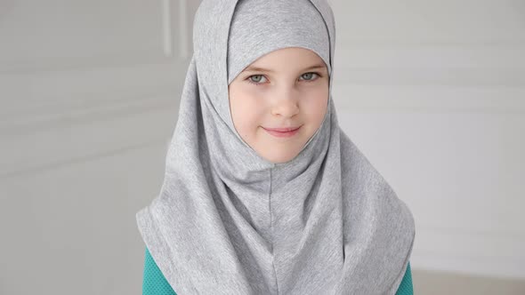 Muslim Girl in Grey Hijab is Looking in Camera and Laughing