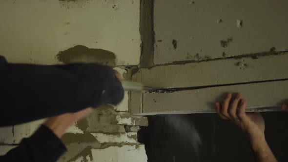 Man's hands sawing a doorway out of foam block with a hand saw