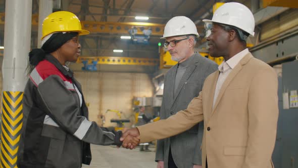 Female Factory Worker Greeting Inspectors with Handshake
