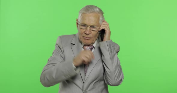 Handsome Elderly Businessman Talks on a Smartphone. Old Man in Suit