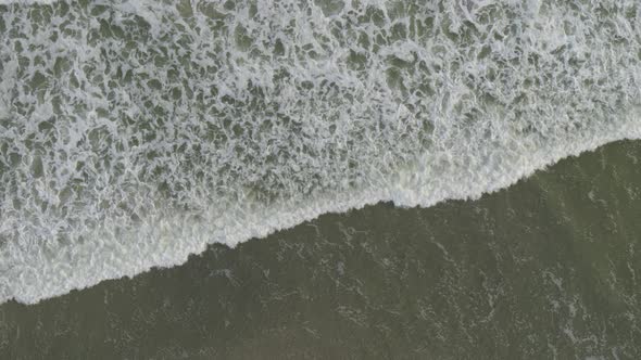 Aerial of frothy waves reaching beach