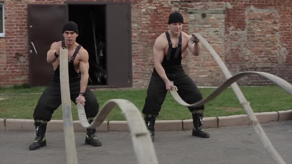 Two Young Muscular Men Training and Do Crossfit Exercises with Battle Ropes. The Camera Zooms in