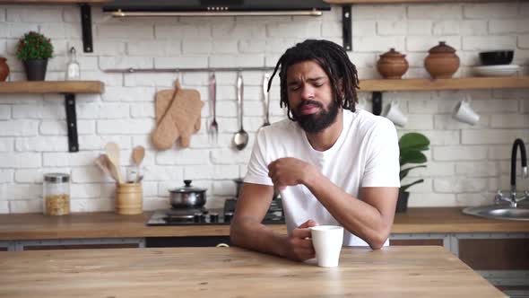 Handsome Young Modern Man African American Yawns and Drinks Coffee in The Kitchen