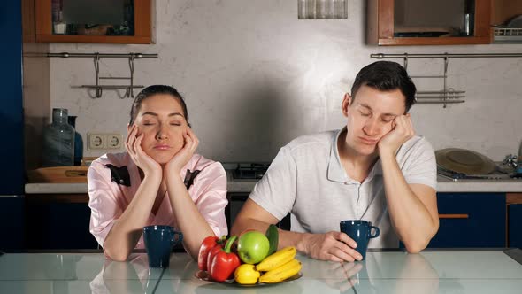 Wife and Husband Sit with Cups of Coffee and Fall Asleep