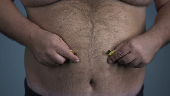 Depressed Fat Male Measuring Huge Tummy, Having Health Issues, Passive Lifestyle